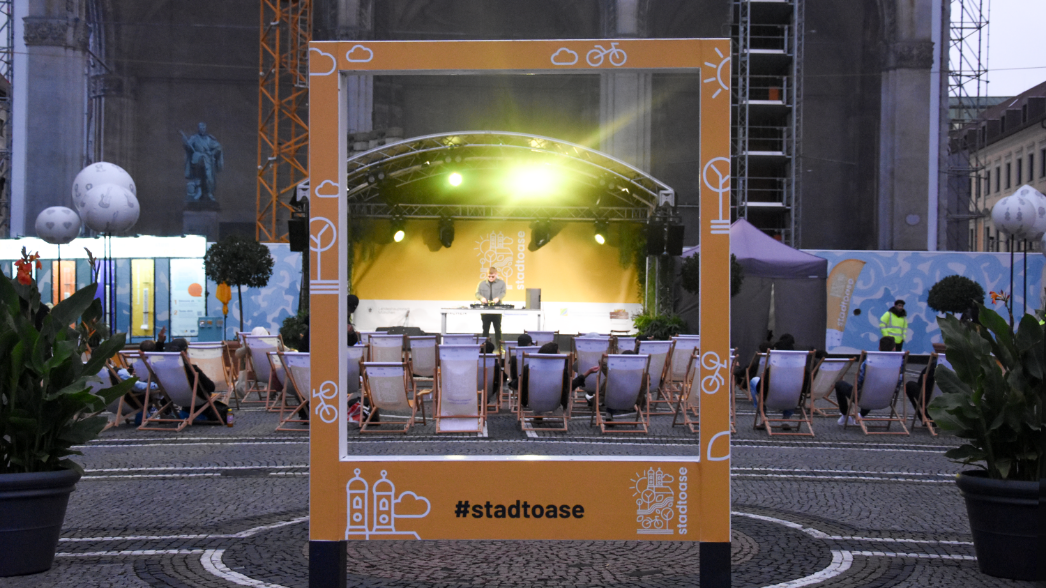 Event / öffentlicher Raum / Klimakommunikation - Raum für Klimaschutz und Mobilität Gelber #stadtoase-Fotorahmen mit Bühne, DJ und Publikum in Liegestühlen auf dem Odeonsplatz vor der Feldherrnhalle